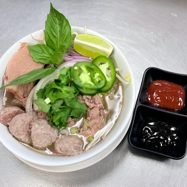 Phatt Pho n' Sushi's pho with beef, meatballs, basil, lime, jalapeños, and sauces.