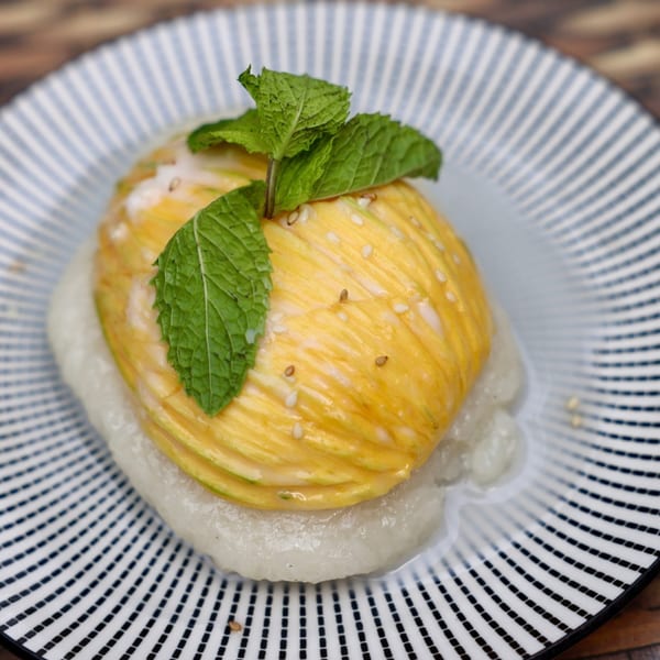 Mango sticky rice dessert with mint garnish on a striped plate at Phatt Pho n' Sushi.