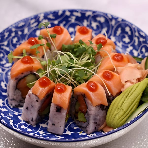 Salmon sushi rolls with red sauce, microgreens, ginger, and wasabi on a blue and white plate.